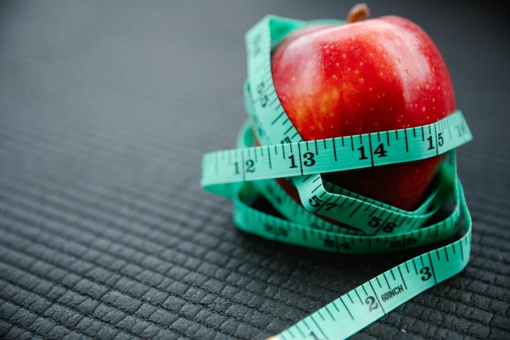 	Red apple wrapped with measuring tape showing health and diet balance