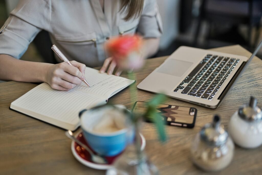 Woman writing to-do list in journal during morning